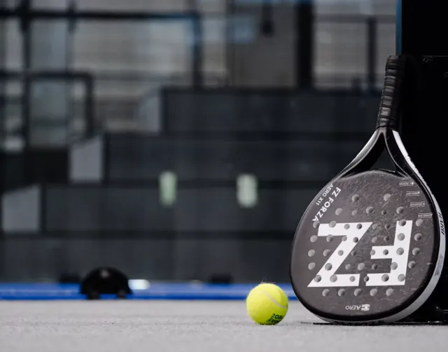 Pala y pelota de pádel sobre una pista