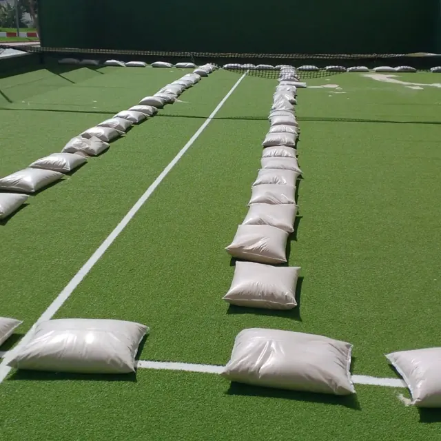Sacos de arena sobre el césped de una pista de pádel